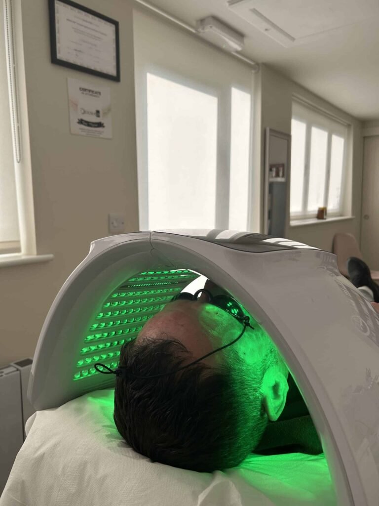 man lying under LED light therapy canopy